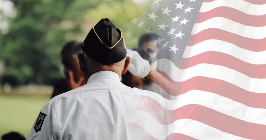 Veteran standing by an American flag.
